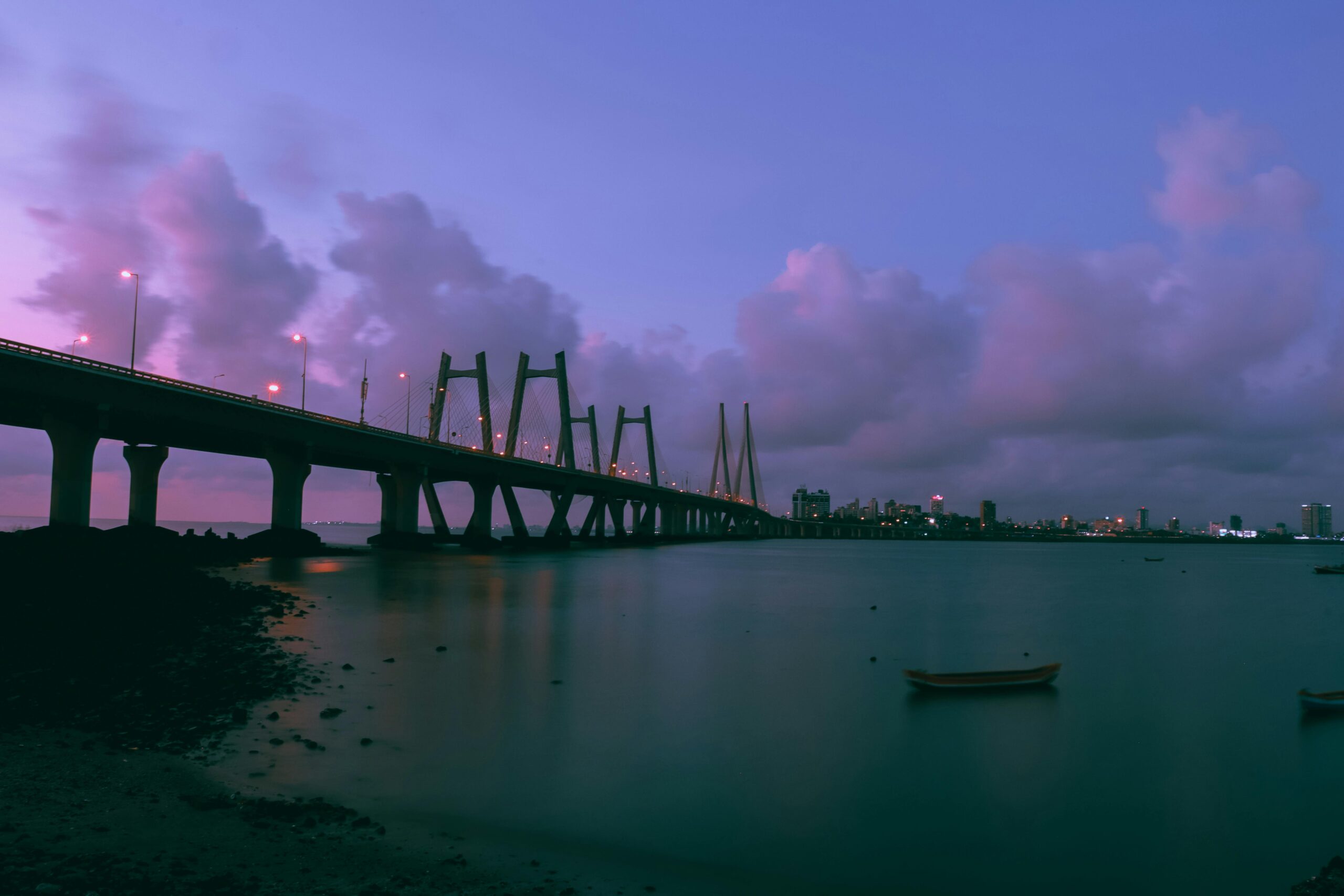 Flat in Mumbai A stunning twilight photograph of an architectural bridge over calm waters, with a vibrant city skyline visible in the background.