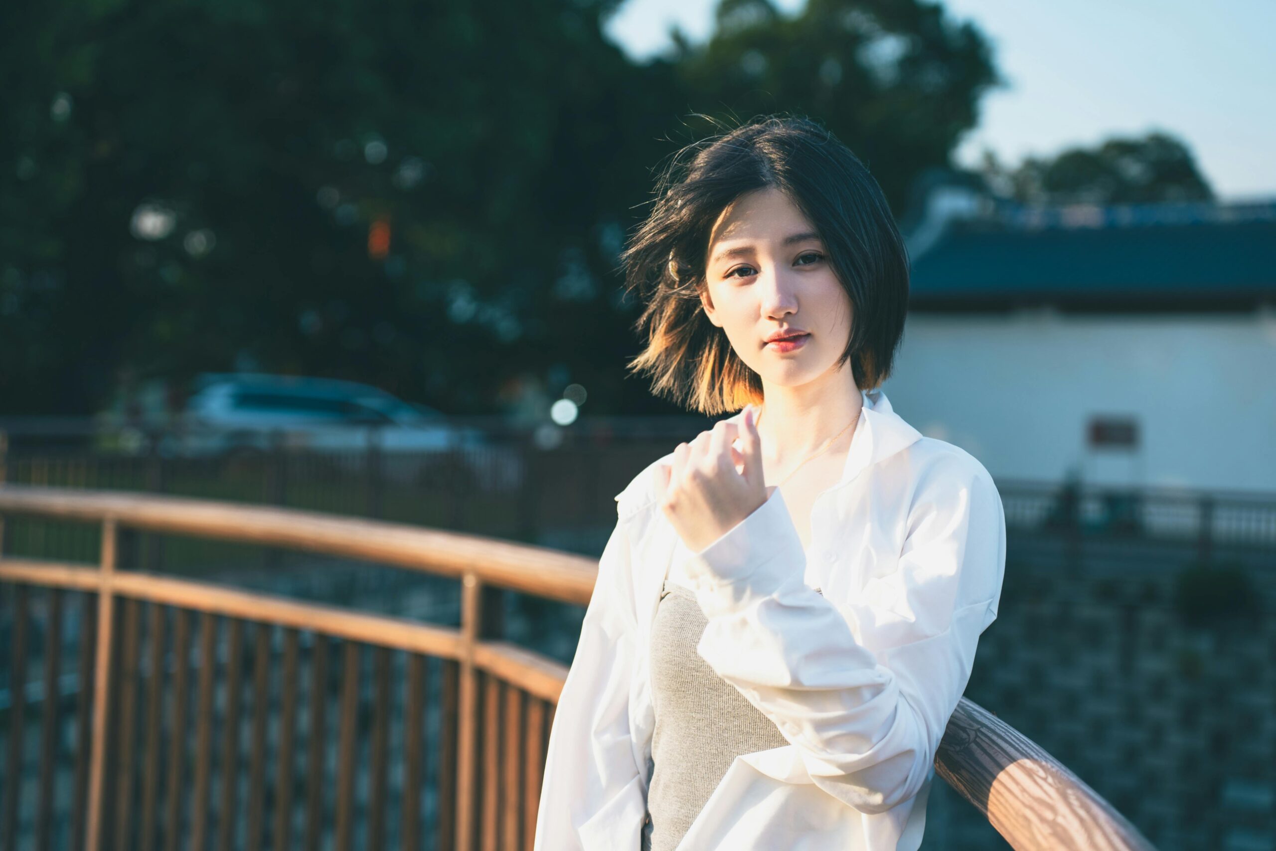 A young woman in casual attire enjoying a sunny day outdoors, standing on a bridge.