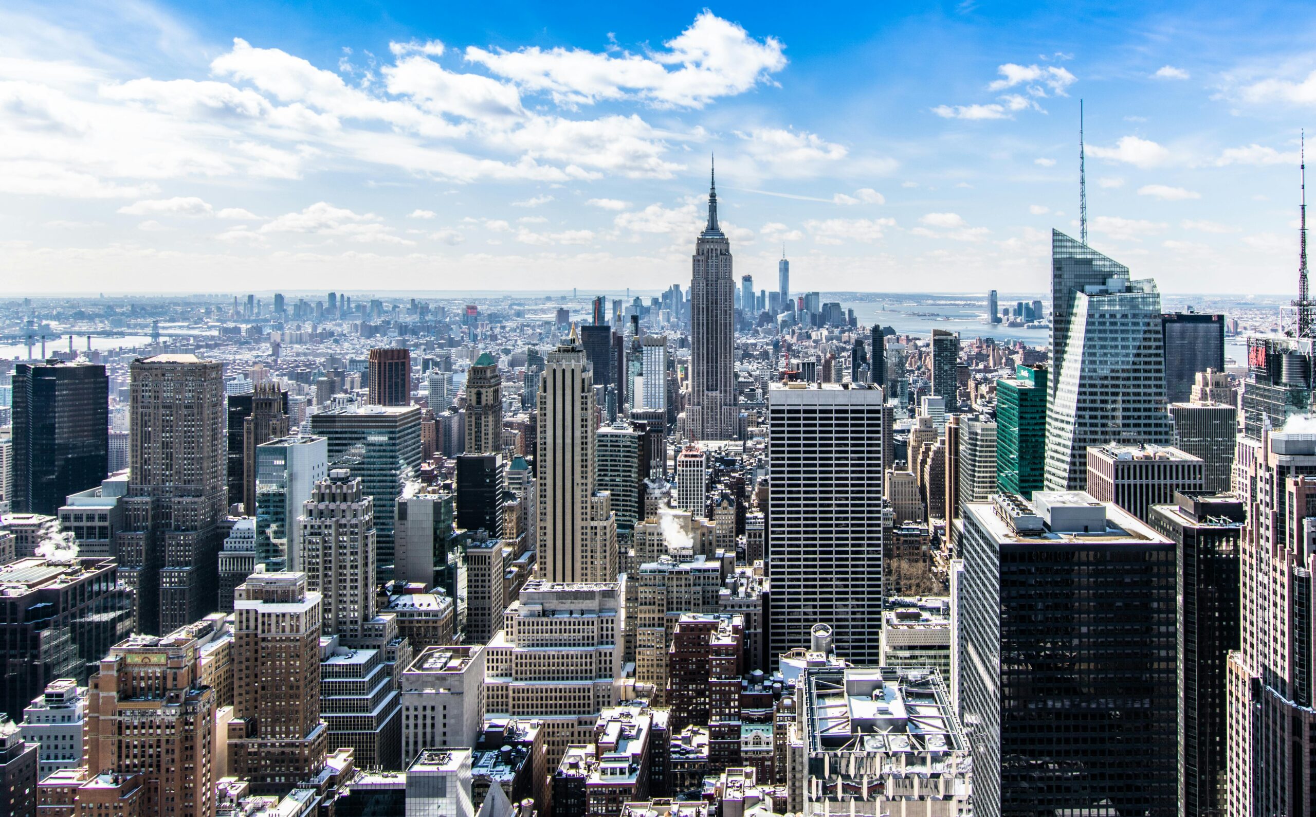 about goproperty A stunning aerial view of New York City's skyline featuring the iconic Empire State Building under a bright blue sky.